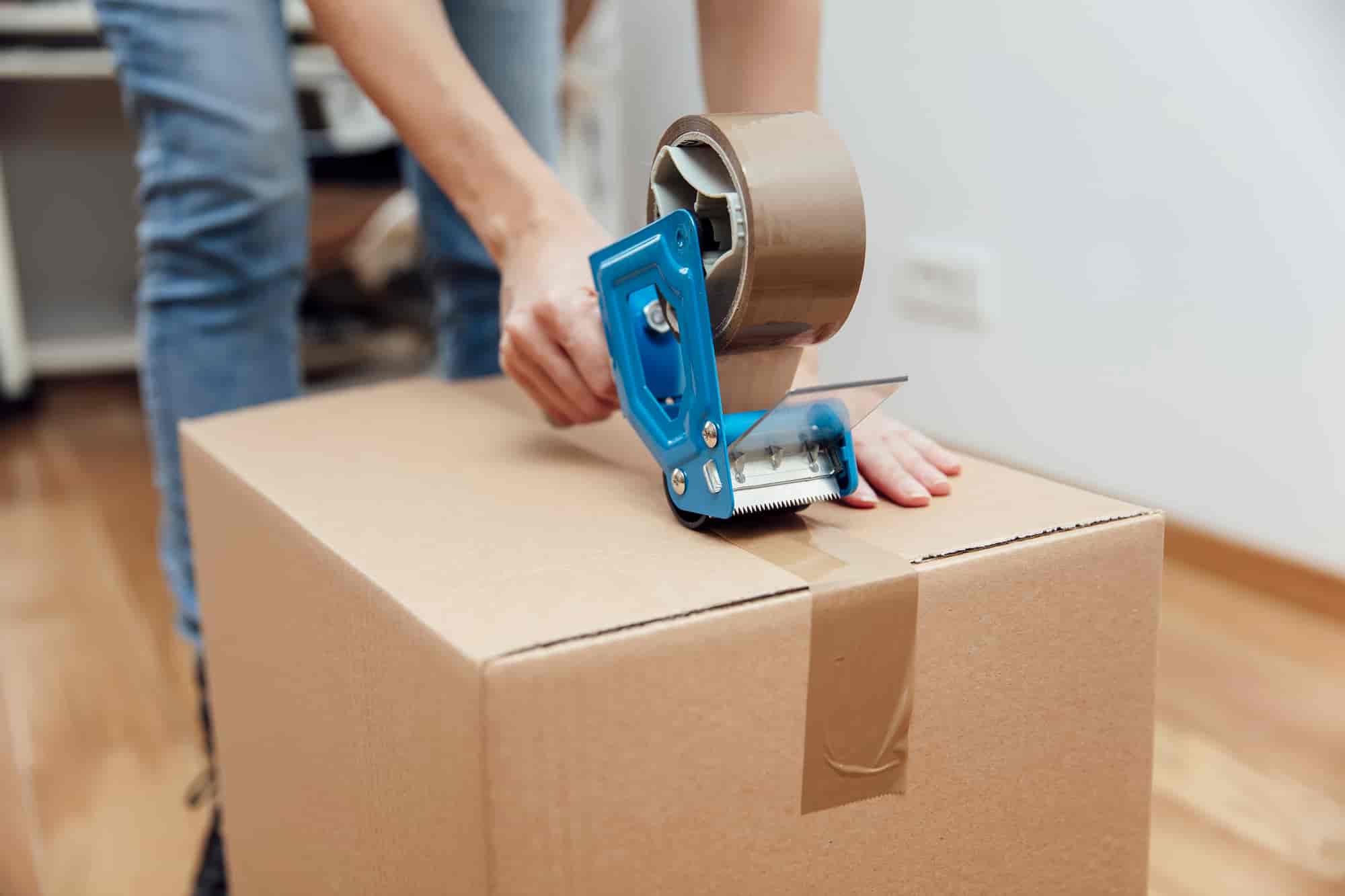 mover packing a box with tape 
