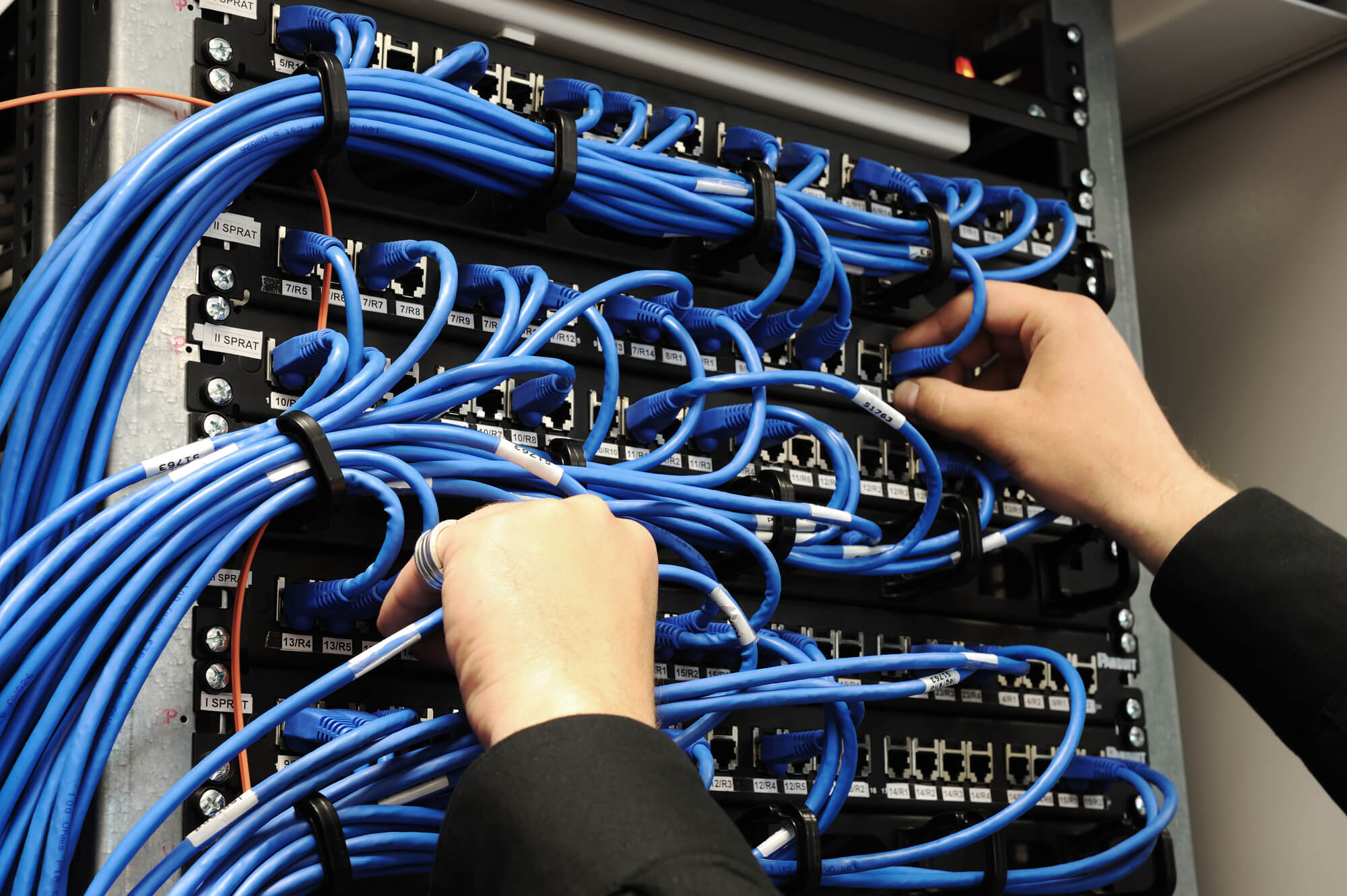 man handling an IT server with blue cables